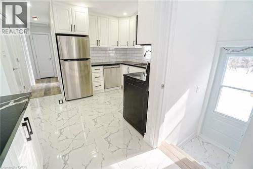 Modern kitchen featuring white shaker cabinetry with black hardware, stainless steel appliances, a subway tile backsplash, and dark stone-look countertops - 8 Marlborough Road, Guelph, ON - Indoor Photo Showing Kitchen