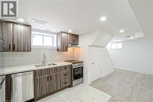 Kitchen area featuring wood-finish cabinetry, light-colored countertops, stainless steel appliances, a subway tile backsplash, and recessed lighting - 8 Marlborough Road, Guelph, ON - Indoor Photo Showing Kitchen