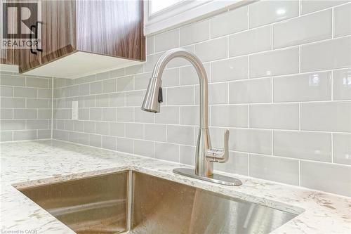 Stainless steel kitchen sink featuring a brushed nickel pull-down faucet, light gray subway tile backsplash, and a light-toned countertop with subtle veining - 8 Marlborough Road, Guelph, ON - Indoor Photo Showing Kitchen With Upgraded Kitchen