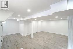 Spacious room featuring light wood-finish flooring, recessed lighting, white walls, and white trim - 