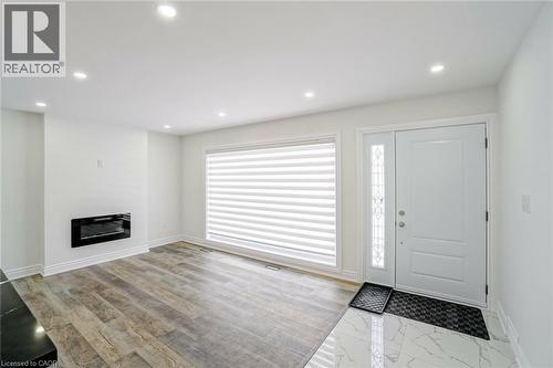 Entryway featuring a white paneled door with decorative sidelight, wood-finish flooring, and recessed ceiling lights - 8 Marlborough Road, Guelph, ON - Indoor With Fireplace