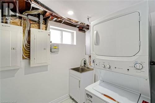 Dedicated laundry area featuring a stacked washer and dryer, utility sink with base cabinetry, and a window for natural light - 8 Marlborough Road, Guelph, ON - Indoor Photo Showing Laundry Room