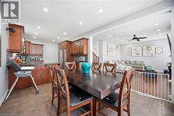 Dining area featuring a dark wood-finish table and chairs, with a kitchen visible featuring wood-finish cabinetry, stainless steel appliances, and dark countertops - 