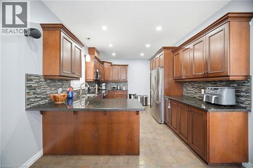 Kitchen featuring wood cabinetry, dark countertops, a mosaic tile backsplash, stainless steel appliances, and recessed lighting - 79 Garinger Crescent, Hamilton, ON - Indoor Photo Showing Kitchen