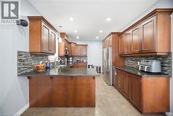 Kitchen featuring wood cabinetry, dark countertops, a mosaic tile backsplash, stainless steel appliances, and recessed lighting - 