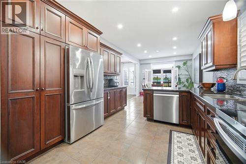 Kitchen featuring abundant wood cabinetry, stainless steel appliances, dark countertops, a mosaic tile backsplash, and recessed lighting - 79 Garinger Crescent, Hamilton, ON - Indoor Photo Showing Kitchen With Upgraded Kitchen
