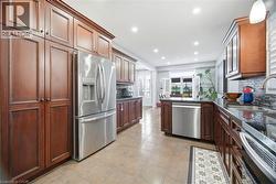 Kitchen featuring abundant wood cabinetry, stainless steel appliances, dark countertops, a mosaic tile backsplash, and recessed lighting - 