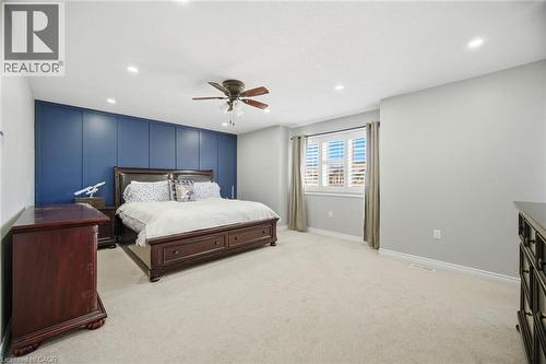 Spacious interior featuring a blue accent wall with panel detailing, light grey walls, and plush carpeting - 79 Garinger Crescent, Hamilton, ON - Indoor Photo Showing Bedroom