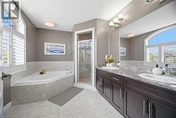 Bathroom featuring a corner soaking tub, a separate glass-enclosed shower, and a dual vanity with dark wood cabinetry - 