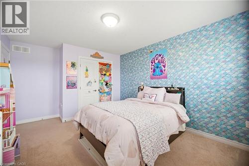 Bedroom featuring a patterned accent wall, light purple painted walls, beige carpet flooring, and a flush mount ceiling light - 79 Garinger Crescent, Hamilton, ON - Indoor Photo Showing Bedroom