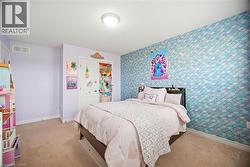 Bedroom featuring a patterned accent wall, light purple painted walls, beige carpet flooring, and a flush mount ceiling light - 