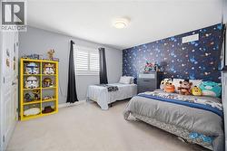 Room featuring a vibrant accent wall with a celestial pattern, light-colored carpet, recessed lighting, and a window with plantation shutters and dark drapes - 