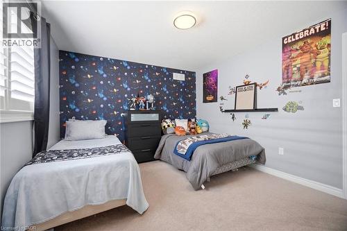Interior room featuring a patterned accent wall, neutral wall paint, white baseboards, and carpeted flooring - 79 Garinger Crescent, Hamilton, ON - Indoor Photo Showing Bedroom