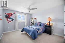 Carpeted bedroom with a ceiling fan, baseboard molding, and a window featuring white plantation shutters - 
