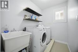 Dedicated laundry room featuring a utility sink with dual-handle faucet, floating shelves, and a window with plantation shutters - 