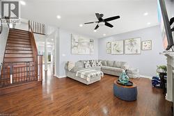 Spacious living area featuring wood-finish flooring, a contemporary ceiling fan, and recessed lighting - 