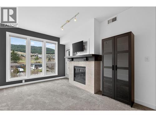 Bright And Modern Living Space With Large Windows, A Cozy Fireplace, And Plenty Of Natural Light - 7343 Okanagan Landing Road Unit# 2402, Vernon, BC - Indoor With Fireplace