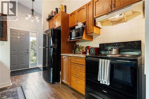 Compact kitchen featuring wood-finish cabinetry and a black appliance suite - 2 Hampton Court, Port Dover, ON - Indoor Photo Showing Kitchen