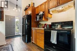 Compact kitchen featuring wood-finish cabinetry and a black appliance suite - 