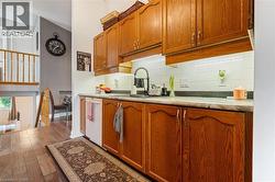 Kitchen featuring wood cabinetry, white tiled backsplash, under-cabinet lighting, and a black faucet at the sink - 