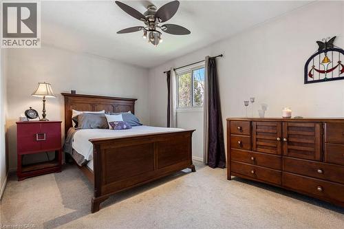 Carpeted room featuring a ceiling fan with integrated lighting, a window with dark drapes, and light-colored walls - 2 Hampton Court, Port Dover, ON - Indoor Photo Showing Bedroom