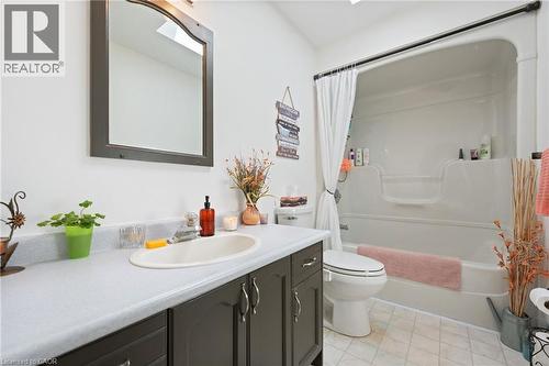 Bathroom featuring a dark wood-finish vanity with an integrated sink, a white countertop, and an arched mirror - 2 Hampton Court, Port Dover, ON - Indoor Photo Showing Bathroom