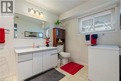 Bathroom featuring a white vanity with integrated sink, rectangular mirror, and three-light fixture - 2 Hampton Court, Port Dover, ON - Indoor Photo Showing Bathroom