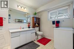 Bathroom featuring a white vanity with integrated sink, rectangular mirror, and three-light fixture - 