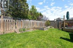 Expansive backyard featuring a manicured lawn, raised garden beds, and a wood privacy fence - 