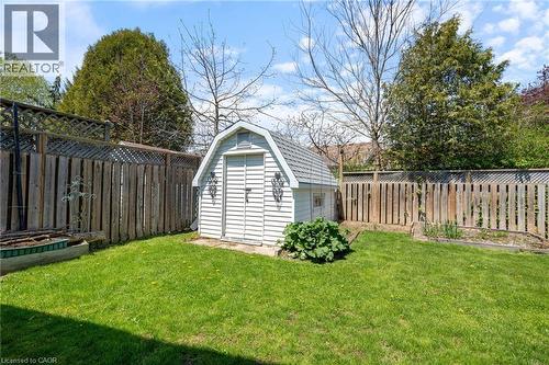 Fenced backyard featuring a white storage shed with barn-style roofing, a raised garden bed, and mature perimeter trees - 2 Hampton Court, Port Dover, ON - Outdoor