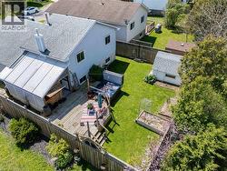 Expansive rear yard featuring a multi-level wood-finish deck with integrated steps, a covered patio area, and a detached storage shed - 