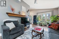 Spacious living area featuring wood-finish flooring, a decorative wood mantelpiece, and a large bay window - 