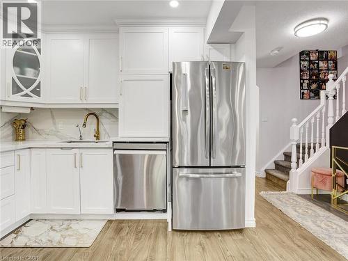 Contemporary kitchen featuring white cabinetry, a gold-finish faucet, and stainless steel appliances, including a dishwasher and refrigerator - 209 Briarmeadow Drive, Kitchener, ON - Indoor Photo Showing Kitchen With Upgraded Kitchen