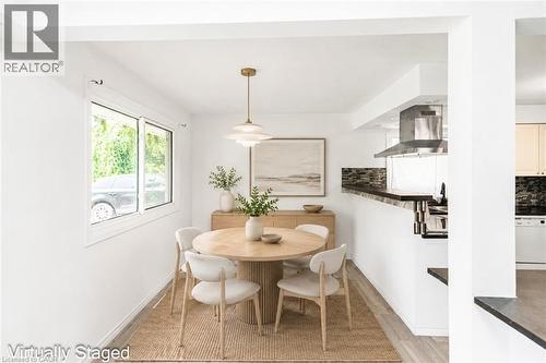 Open-concept dining area featuring wood-finish flooring, a contemporary pendant light fixture, and a large sliding window - 100 Mountain Avenue N, Hamilton, ON - Indoor Photo Showing Dining Room