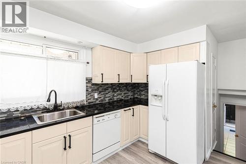 Kitchen featuring cream-colored cabinetry, dark countertops, a mosaic tile backsplash, and wood-finish flooring - 100 Mountain Avenue N, Hamilton, ON - Indoor Photo Showing Kitchen