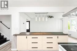 Kitchen island featuring light-toned cabinetry with dark hardware and a dark countertop - 