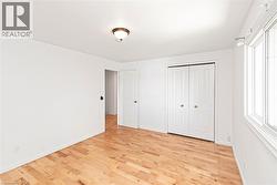 Bright interior space featuring wood-finish flooring, white walls, and a ceiling-mounted light fixture - 