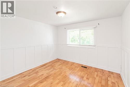 Room featuring wood-finish flooring, white board and batten wall detailing, a window with blinds, and a flush-mount ceiling light fixture - 100 Mountain Avenue N, Hamilton, ON - Indoor Photo Showing Other Room