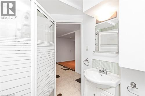 Spa-inspired primary bathroom featuring a frameless glass-enclosed shower with horizontal tile detailing, pedestal sink with chrome fixtures, recessed lighting, and neutral tile flooring throughout - 100 Mountain Avenue N, Hamilton, ON - Indoor Photo Showing Bathroom