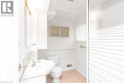 Bathroom featuring a pedestal sink with chrome fixtures, a tiled backsplash, and recessed wall cabinetry - 