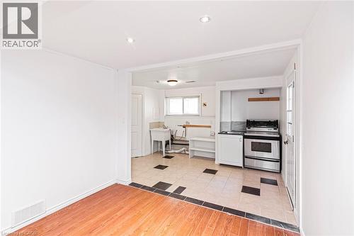 Open concept living area featuring wood-finish flooring, recessed lighting, and a kitchen area with tile flooring, a stainless steel range, and a utility sink - 100 Mountain Avenue N, Hamilton, ON - Indoor