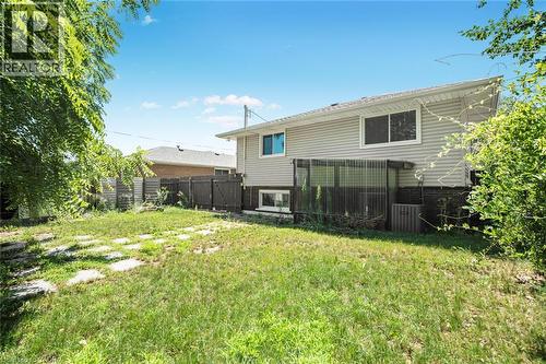 Expansive backyard featuring a stone paver pathway, mature perimeter greenery, and a light-colored vinyl siding exterior - 100 Mountain Avenue N, Hamilton, ON - Outdoor