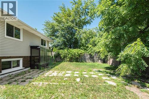 Spacious rear yard with a perimeter fence, mature trees, and an established paved patio area - 100 Mountain Avenue N, Hamilton, ON - Outdoor