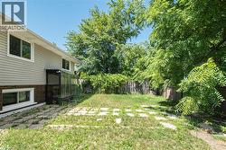 Spacious rear yard with a perimeter fence, mature trees, and an established paved patio area - 