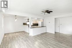 Open-concept living space featuring wood-finish flooring, white walls, and a ceiling fan - 