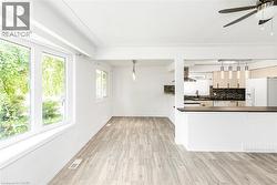 Open-concept living area with wood-finish flooring, white walls, and exposed ceiling beams - 