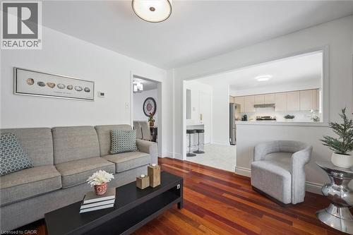 Open-concept living space featuring wood-finish flooring, a contemporary ceiling light fixture, and a pass-through to the kitchen - 5147 Ravine Crescent, Burlington, ON - Indoor Photo Showing Living Room