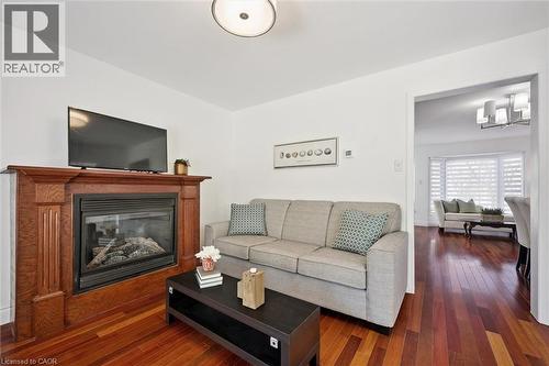 Living area featuring a wood-finish fireplace surround, a built-in fireplace insert, and rich wood-finish flooring - 5147 Ravine Crescent, Burlington, ON - Indoor Photo Showing Living Room With Fireplace