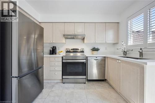 Kitchen featuring light-toned cabinetry with light countertops, stainless steel appliances, and tiled flooring - 5147 Ravine Crescent, Burlington, ON - Indoor Photo Showing Kitchen With Double Sink