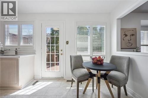 Bright room featuring a white paneled door with glass inserts, two windows with white plantation shutters, and light-toned tile flooring - 5147 Ravine Crescent, Burlington, ON - Indoor Photo Showing Dining Room